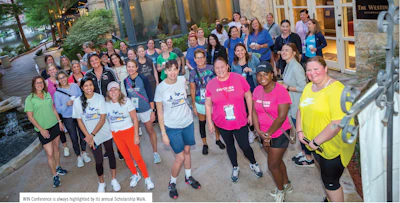 Large group of diverse participants gathered for a scholarship walk event outside a building