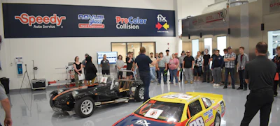 Auto service center interior with classic cars and group of people gathered