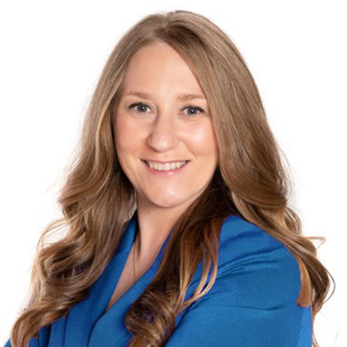 Professional woman in blue blazer smiling with wavy brown hair