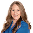 Professional woman in blue blazer smiling with wavy brown hair