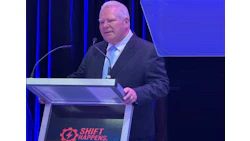 Speaker at Shift Happens conference presenting at a blue-lit podium