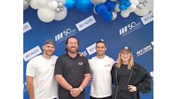 Four team members posing at 427 Auto corporate event with blue and white balloon backdrop
