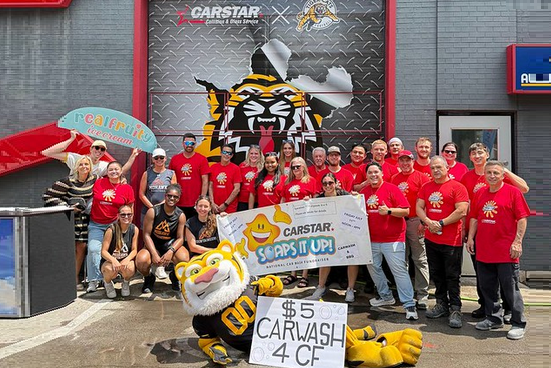 CARSTAR charity car wash event with team in red shirts and mascot