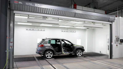Gray SUV with open doors inside a white automotive testing chamber