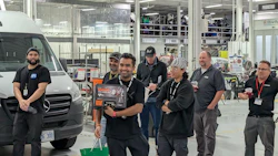Team of workers standing near a white van in an industrial manufacturing facility