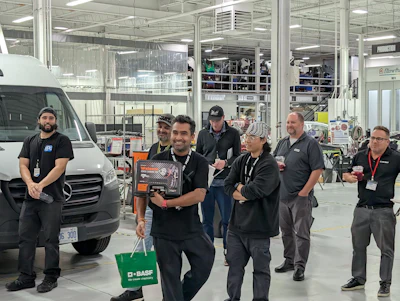 Team of workers standing near a white van in an industrial manufacturing facility