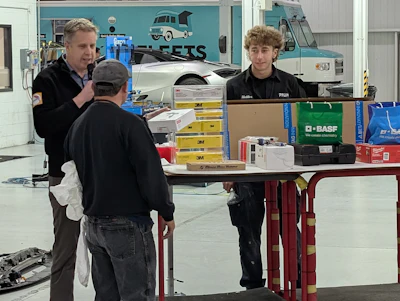 Auto repair shop interior with workers and product displays on workbench