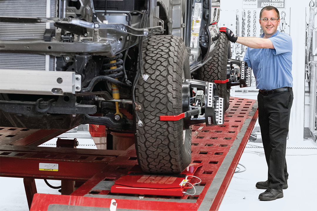 Automotive technician performing tire alignment on vehicle chassis