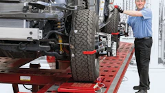 Automotive technician performing tire alignment on vehicle chassis