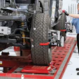 Automotive technician performing tire alignment on vehicle chassis