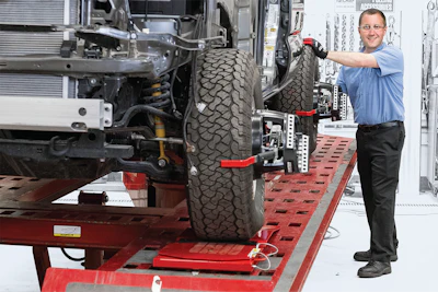 Automotive technician performing tire alignment on vehicle chassis