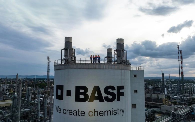 BASF chemical plant storage tank with industrial facility in background under cloudy skies