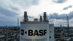 BASF chemical plant storage tank with industrial facility in background under cloudy skies