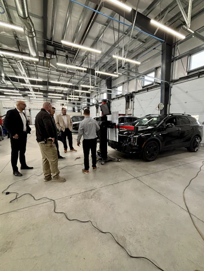 Black SUV on lift in automotive service center with technicians discussing vehicle