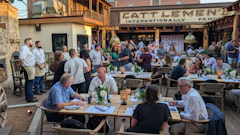 Crowded outdoor dining area at Cattlemen's restaurant with people seated at wooden tables