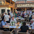 Crowded outdoor dining area at Cattlemen's restaurant with people seated at wooden tables