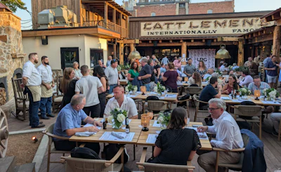 Crowded outdoor dining area at Cattlemen's restaurant with people seated at wooden tables