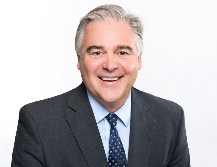 Smiling professional in gray suit and blue tie against white background