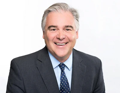 Smiling professional in gray suit and blue tie against white background