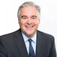 Smiling professional in gray suit and blue tie against white background