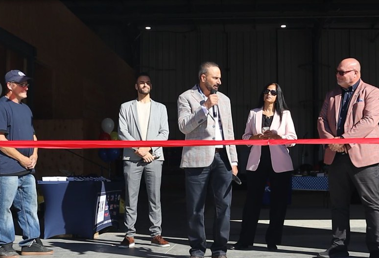 Business professionals at a ribbon-cutting event with red ribbon