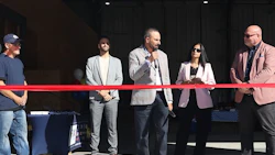 Business professionals at a ribbon-cutting event with red ribbon