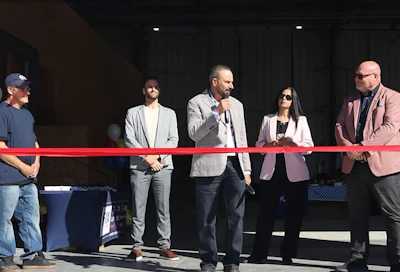 Business professionals at a ribbon-cutting event with red ribbon