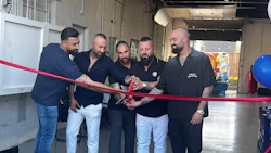 Five men cutting a red ribbon at a business opening or launch event