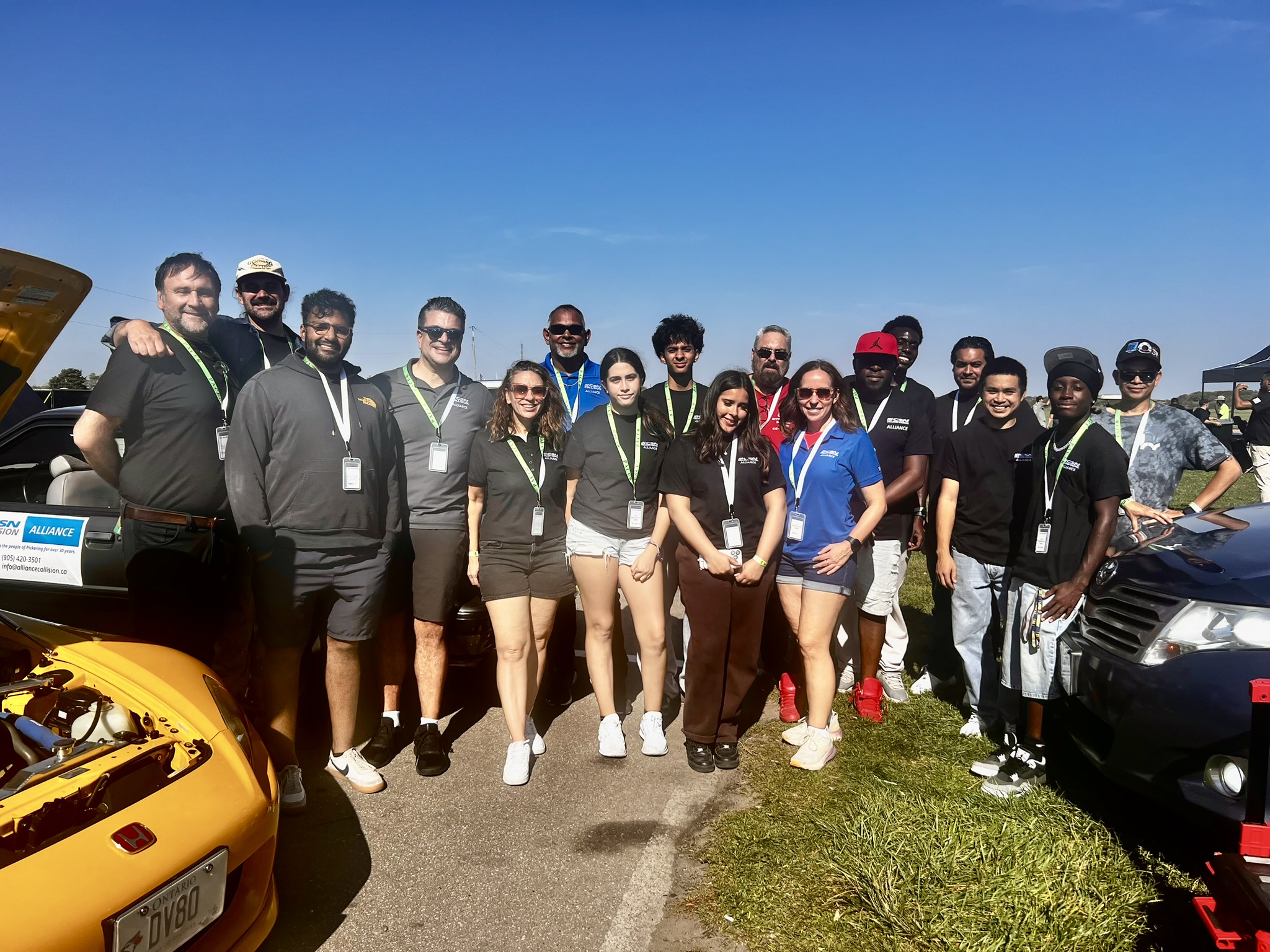 Diverse group of team members standing near vehicles on a sunny day