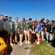 Diverse group of team members standing near vehicles on a sunny day