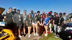 Diverse group of team members standing near vehicles on a sunny day