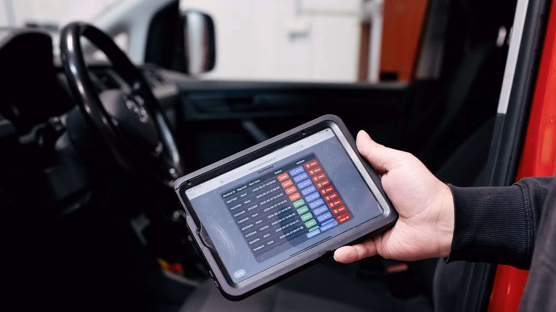 Hand holding tablet displaying data metrics inside a vehicle dashboard