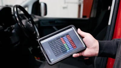 Hand holding tablet displaying data metrics inside a vehicle dashboard