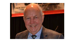 Smiling senior man in brown suit and tie at a professional event