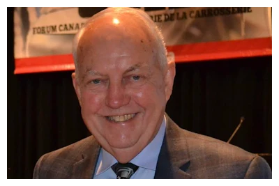 Smiling senior man in brown suit and tie at a professional event
