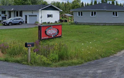 Red Original logo sign in front yard with residential houses and trees