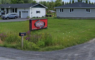 Red Original logo sign in front yard with residential houses and trees