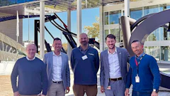 Six professionals standing together in a modern office building lobby
