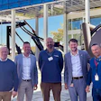 Six professionals standing together in a modern office building lobby