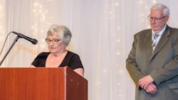 Senior speakers at a podium during a formal presentation event