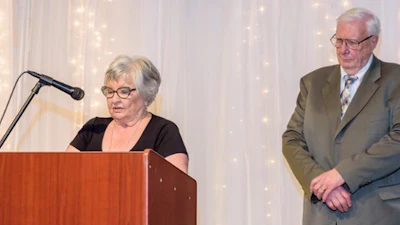 Senior speakers at a podium during a formal presentation event