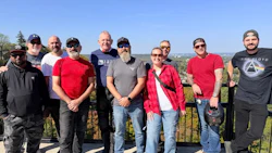 Group of diverse adults standing together on an outdoor terrace with scenic background