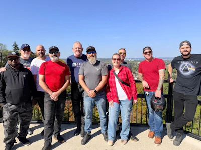 Group of diverse adults standing together on an outdoor terrace with scenic background