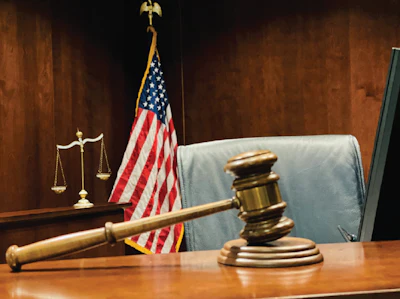 Judicial gavel, scales of justice, and American flag in courtroom setting