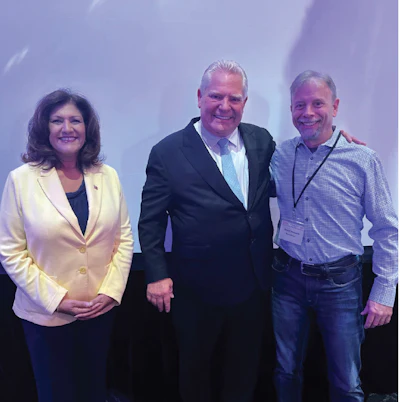 Three professionals posing together at a conference or event, smiling