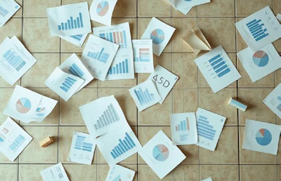 Business analytics documents with bar graphs and pie charts spread across floor tiles
