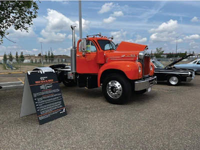 Classic orange vintage truck on display at outdoor parking lot with informational sign