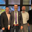 Five businessmen in professional attire standing together in modern office lobby