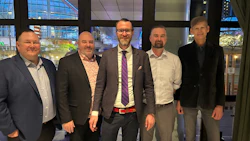 Five businessmen in professional attire standing together in modern office lobby