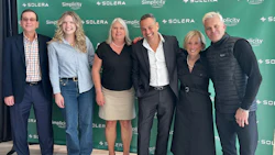 Six professionals posing in front of Solera corporate green step-and-repeat backdrop